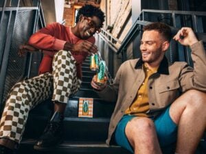 two black gay men sitting on front steps drinking Hornitos