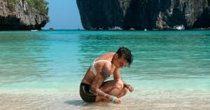 lesbian woman kneeling down in the bright blue water on a edge of a beach in thailand.JPG