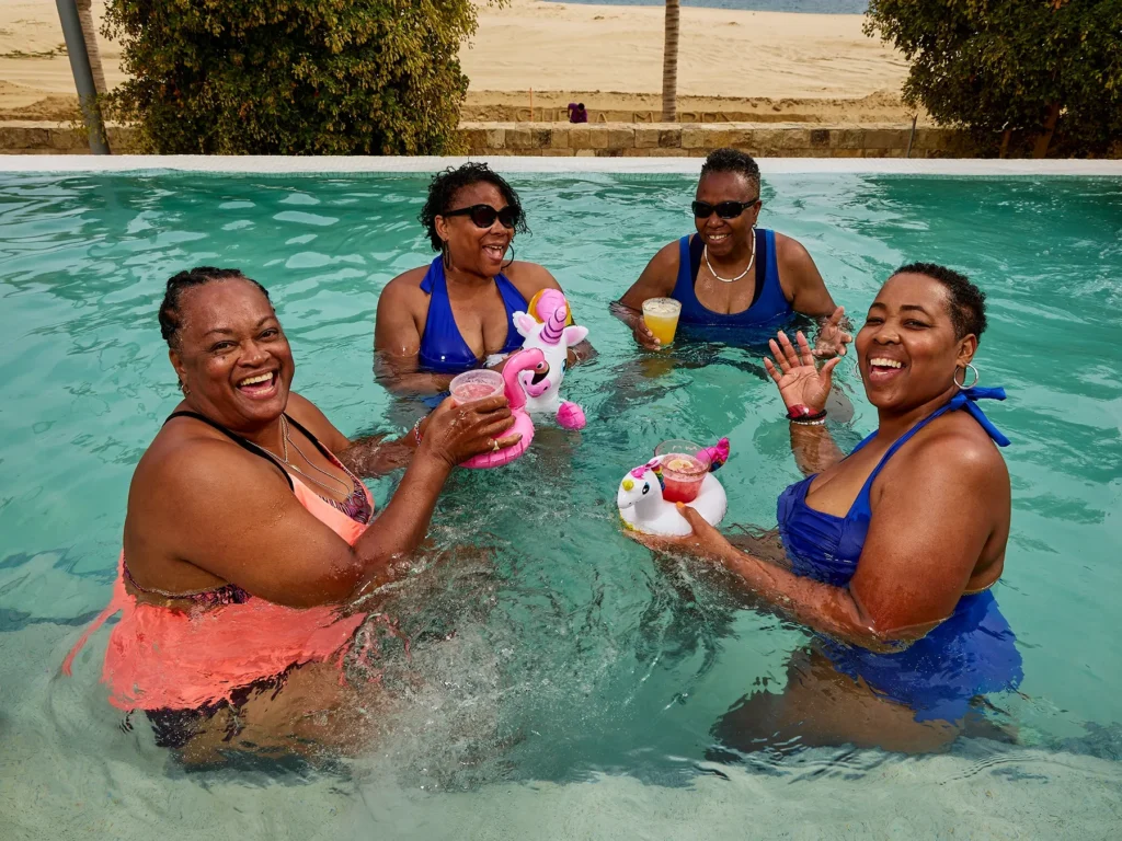 Four LGBTQ women in a pool holding cocktails in unicorn floatings
