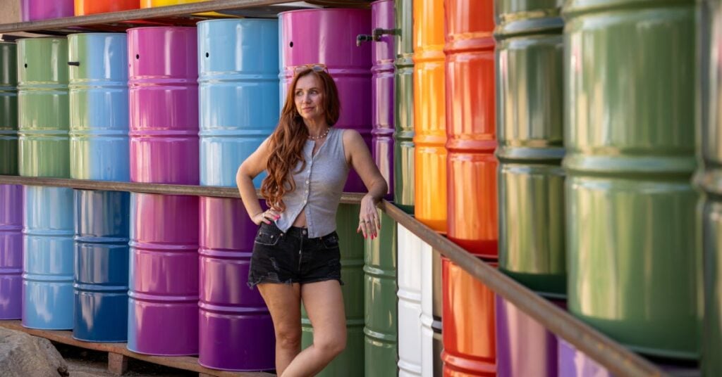 queer woman standing in front of brightly colored barrels at the LAB in Costa Mesa California