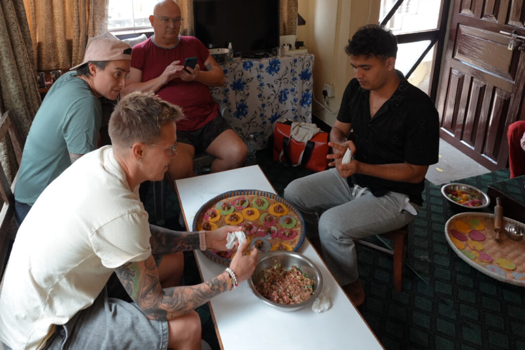 queer people sitting around a platter of momos in a home in Nepal