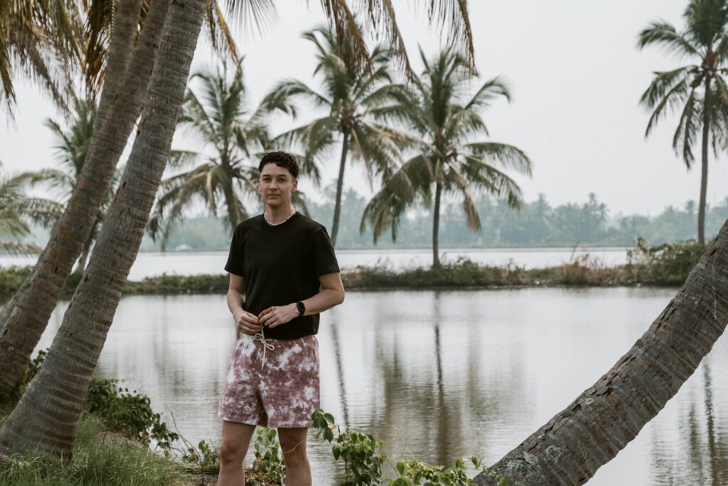 Gender non conforming person standing near palm trees in Kerla India