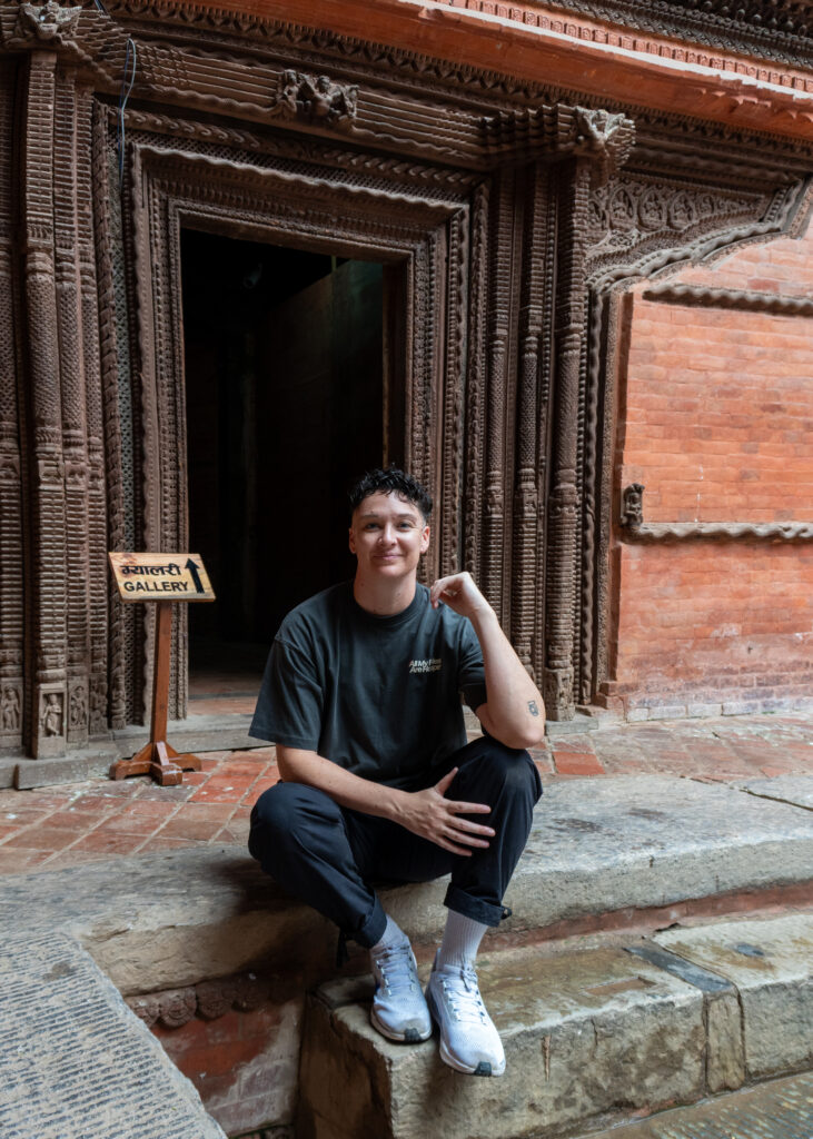 masc presenting lesbian woman sitting on a stoop in Nepal