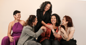 group of lesbians laughing and smiling with each other. they are dressed in business casual attire